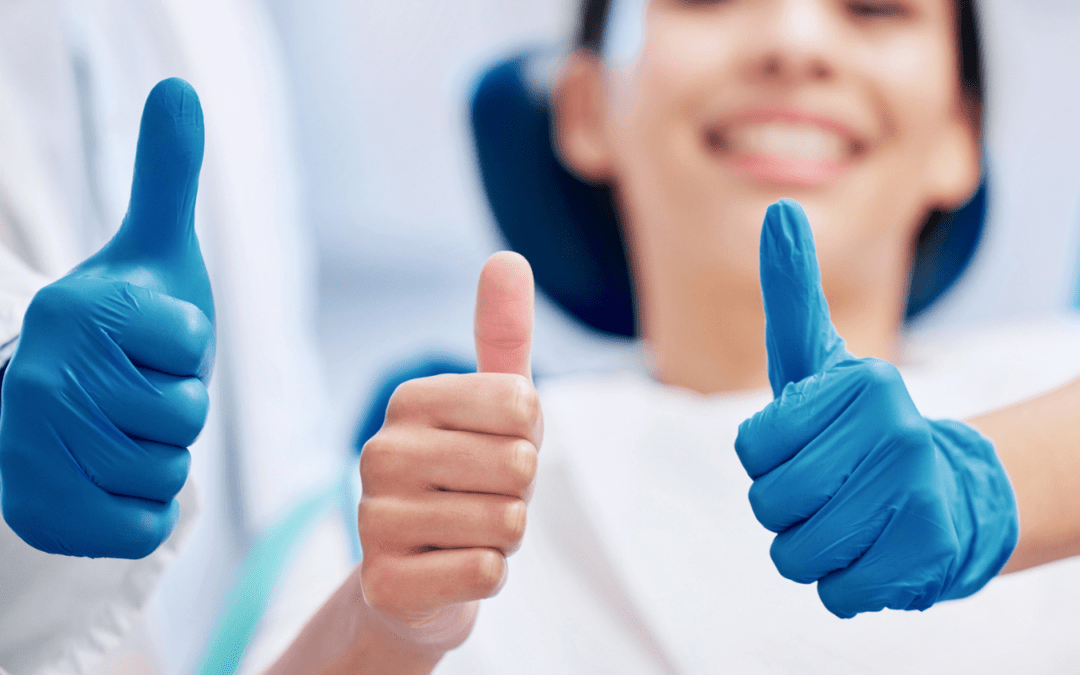 Patient smiling with dentist, both giving thumbs up.
