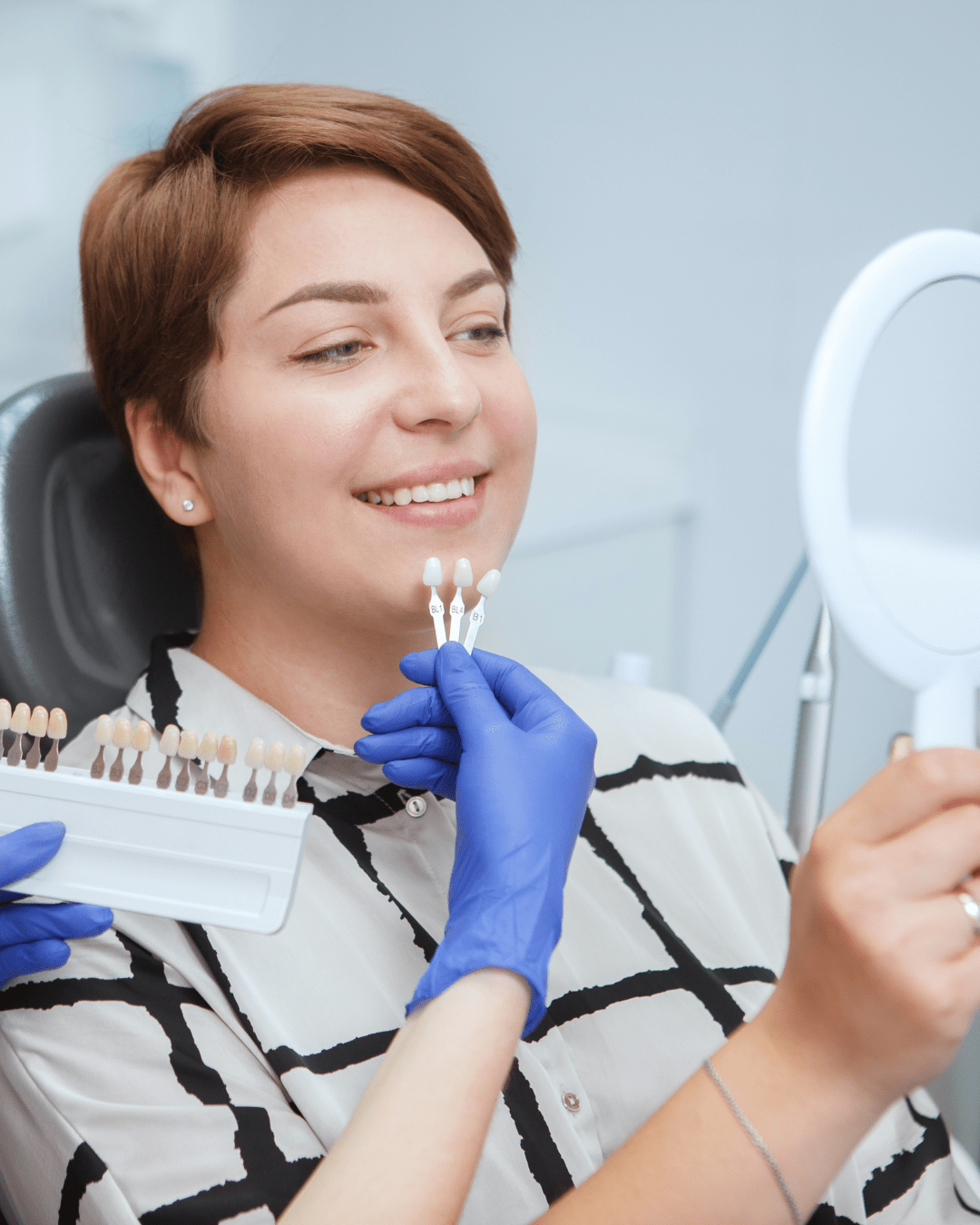 dentist helping female patient pick teeth whitening shade from the chart